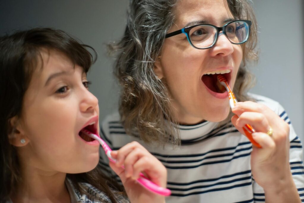 woman and child brushing their teeth together